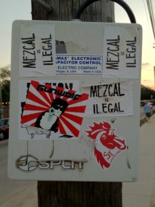 Stickers reading "Mezcal is Ilegal" on a telephone pole near Clives in Austin, TX.