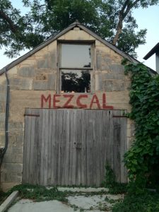 The word "Mezcal" painted onto a barn at Clive Bar in Austin, TX.