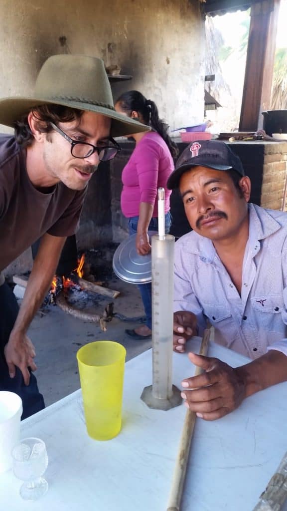 A photo of NETA co-founder Max Rosenstock as he discusses and upcoming batch of mezcla with maestro mezcalero Eliazar Garzia Vasquez.